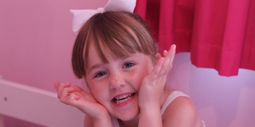 Little girl smiling in her pink bedroom