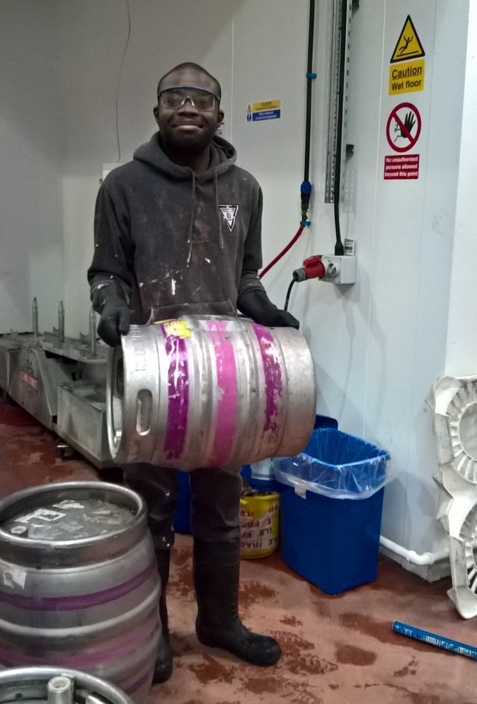 Young man carrying a metal barrel