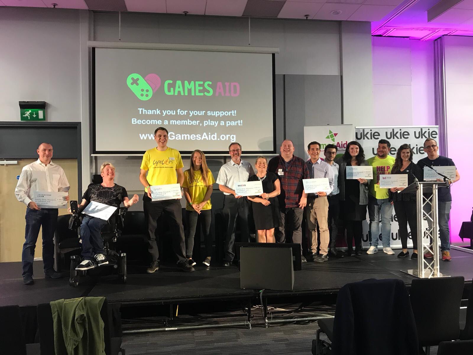 jamie green gamesaid Group on stage holding cheques at an awards ceremony