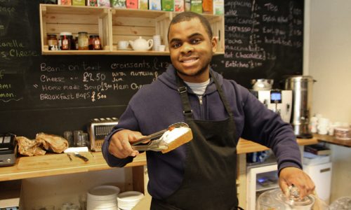 Young man seriving cake from a cafe counter