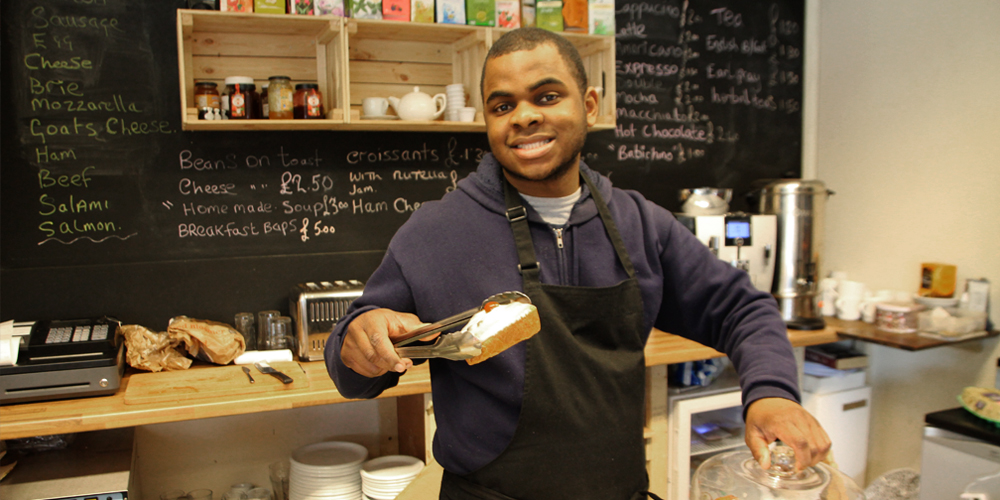 Young man seriving cake from a cafe counter