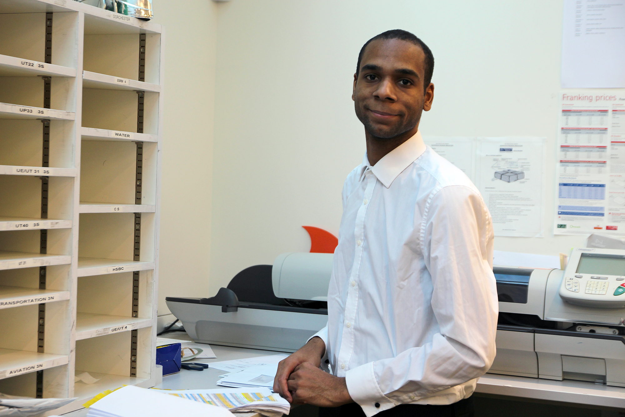 Young man smiling at work in the post room