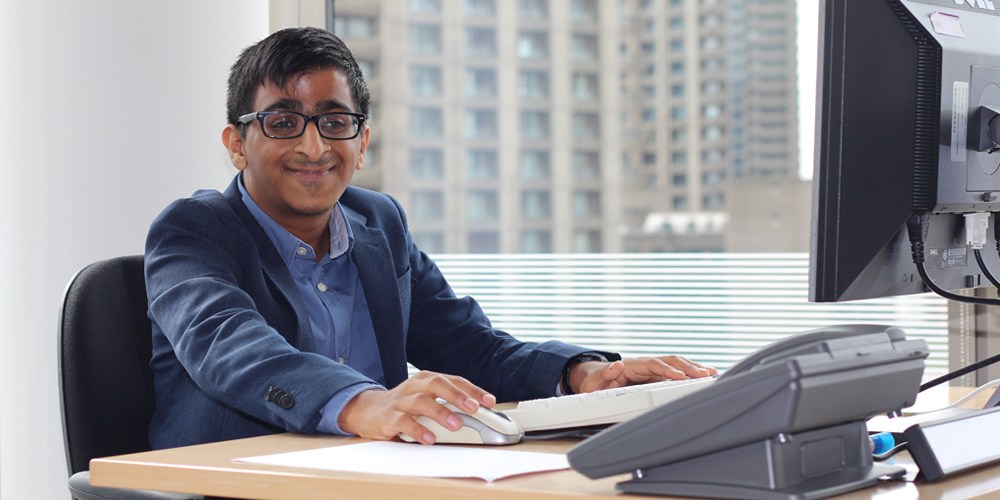 Nirav law firm banner Young man sitting at a computer desk at a law firm