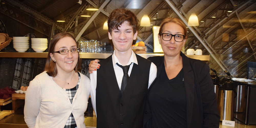 Young man with learning disabilities at work in a hotel with two coworkers