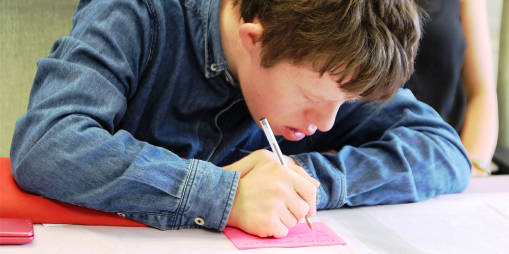 Male student with learning disabilities writing on a piece of paper