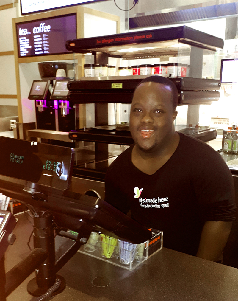 A young man with Down Syndrome working behind the tills at an Itsu sushi restaurant