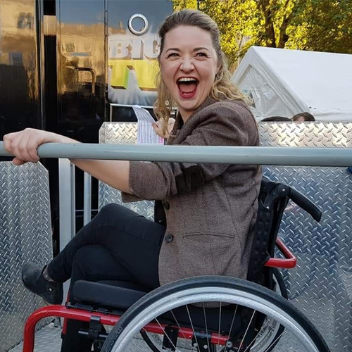 Dr Hannah Barham-Brown smiling in her red wheelchair