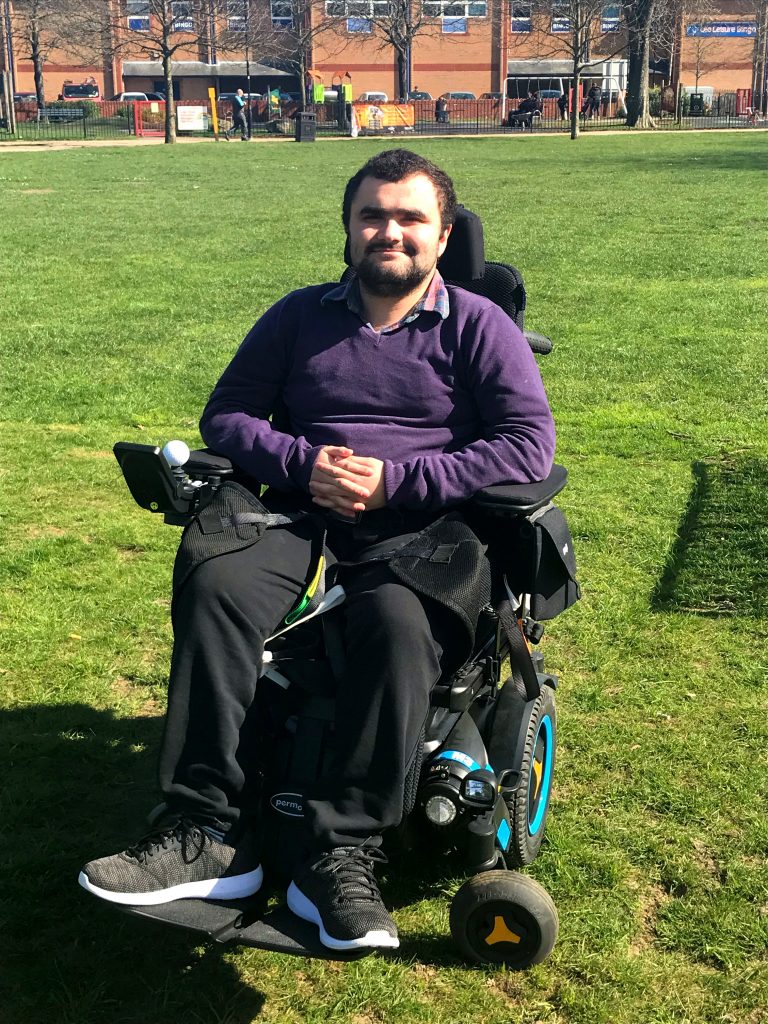 man sitting in powerchair on grass