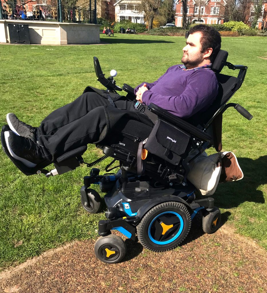 man leaning back in powerchair on grass