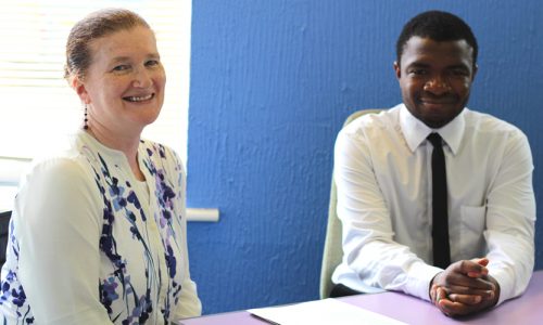 Woman and young man sitting at a table smiling