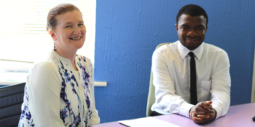 Woman and young man sitting at a table smiling