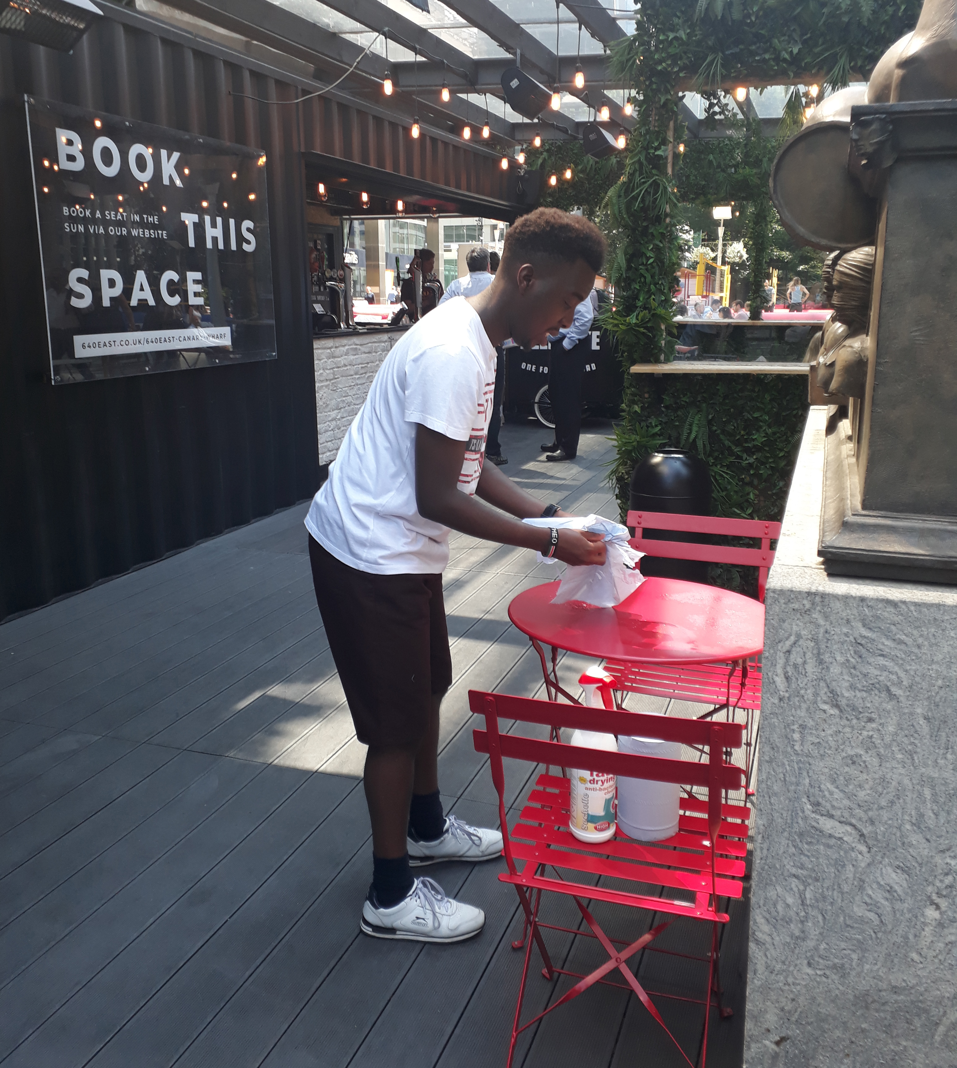 young man cleaning tables at a cafe bar