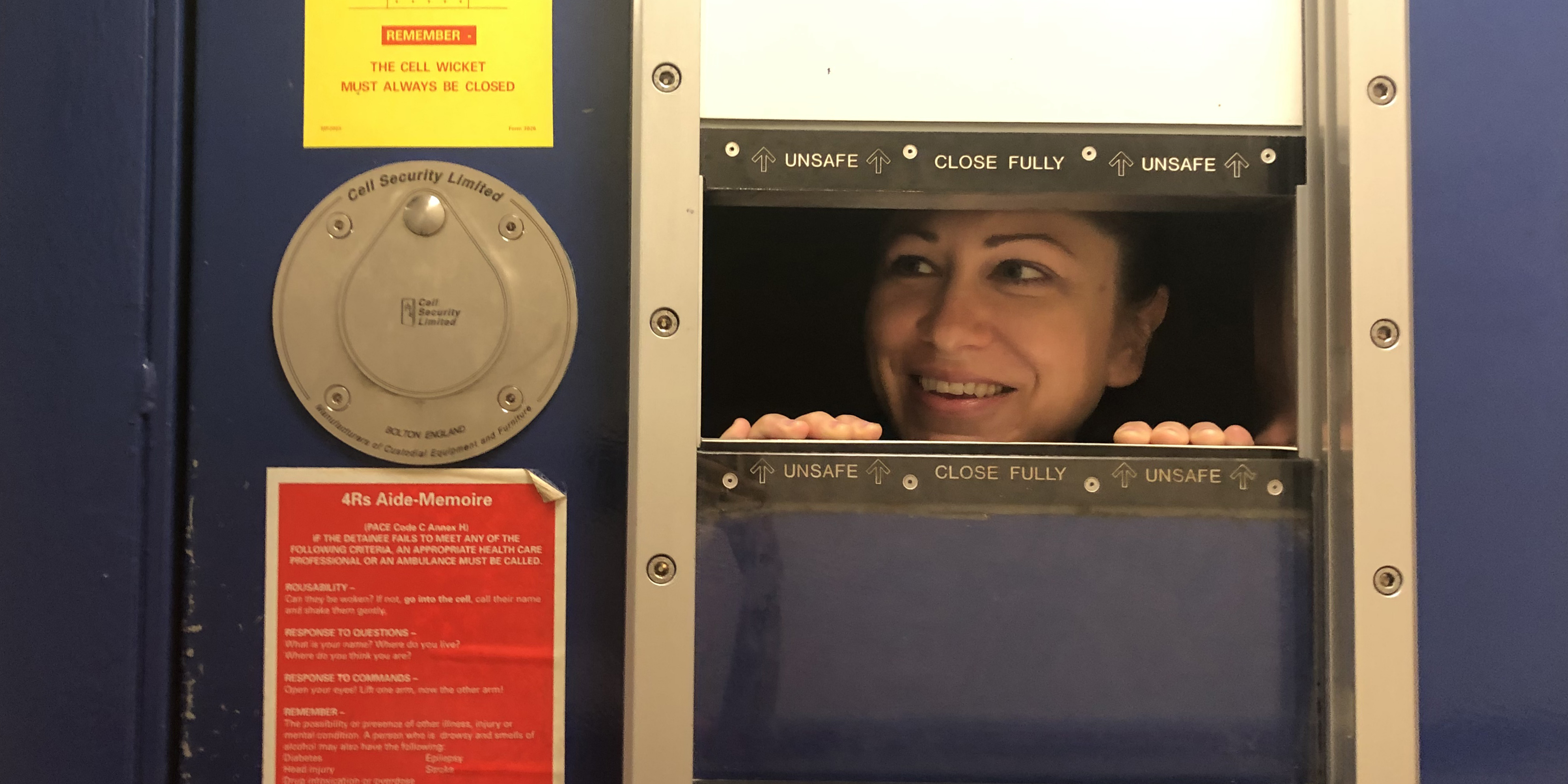 Laura peeping through a prison cell door