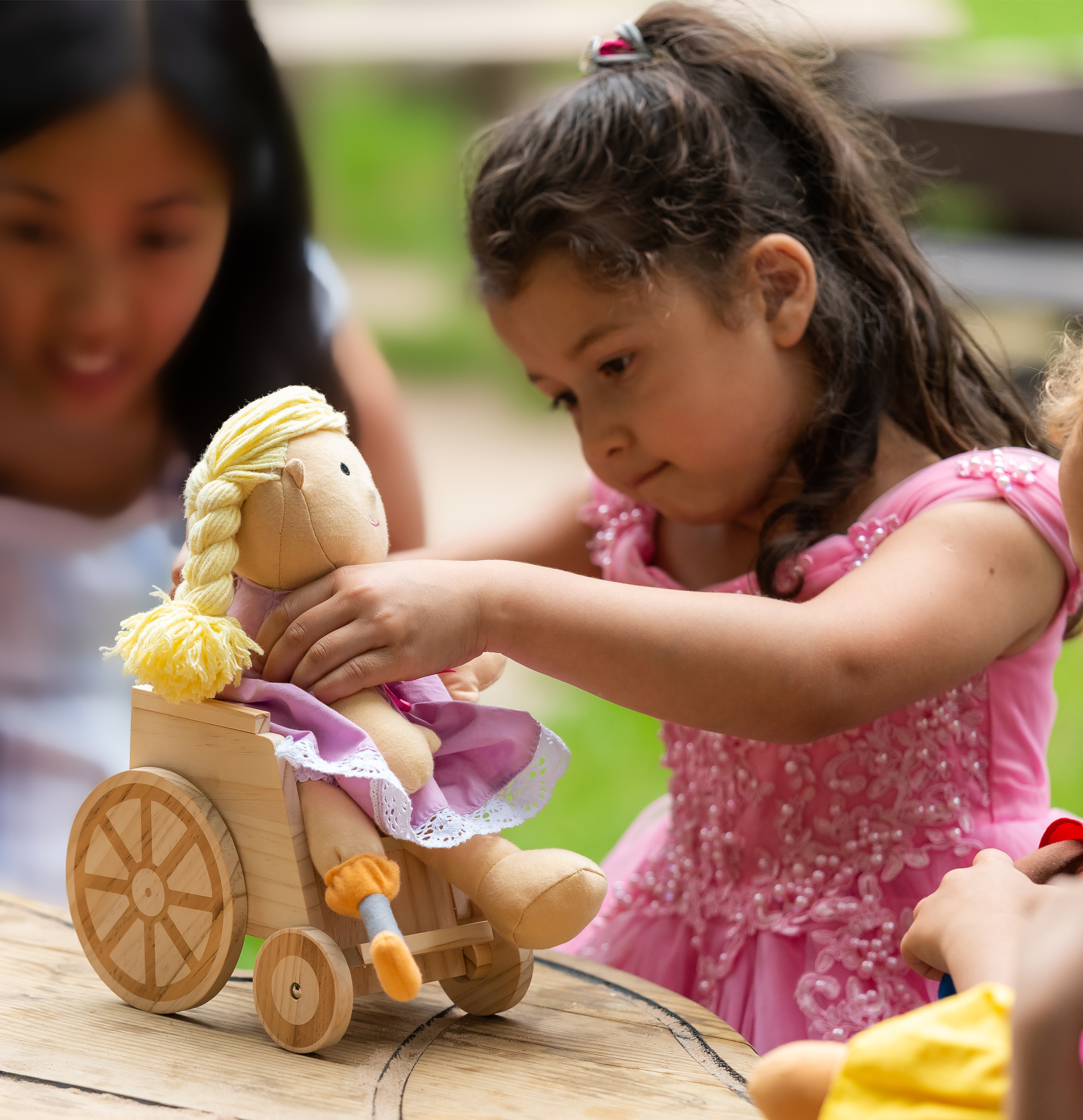 little girl playing with a doll that has a prosthetic leg and is in a wheelchair