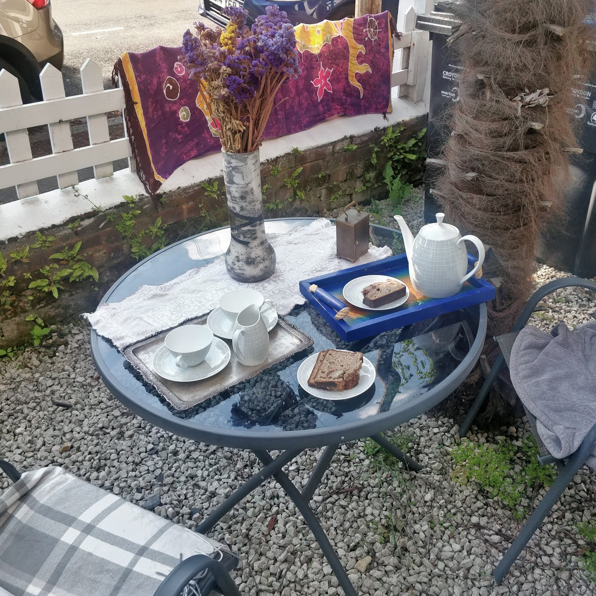 A patio table with tea and cake in a gravelled front garden