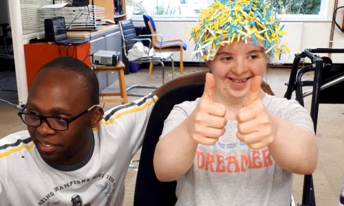 two young people smiling and giving thumbs up