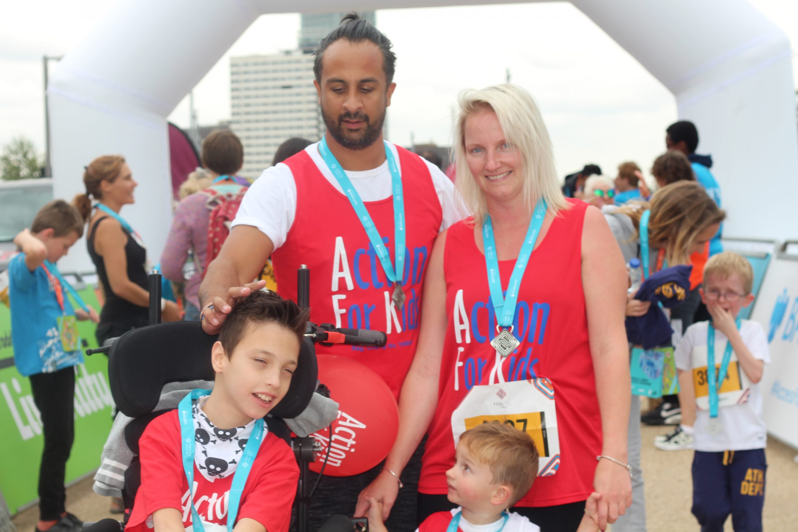 Family wearing red AFK vests and medals at Parallel London finish line
