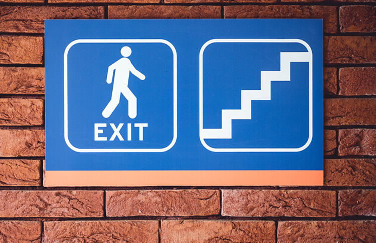 blue exit sign on a brick wall