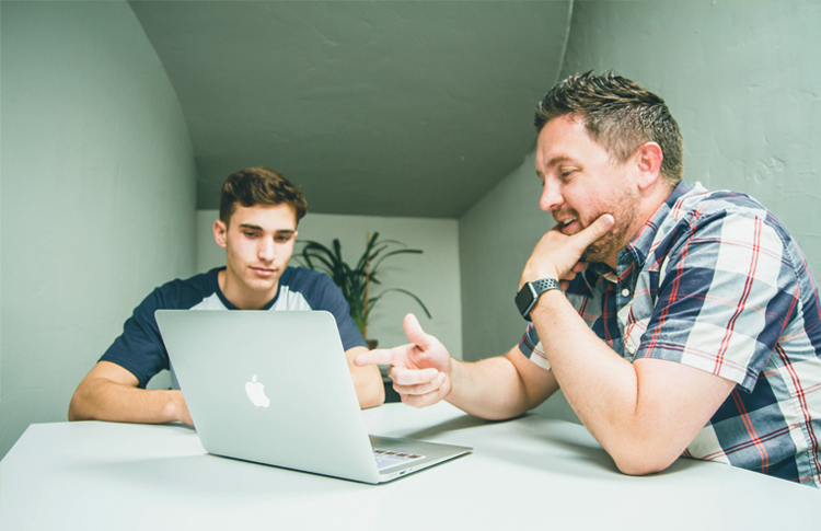 Two young men sitting at a laptop