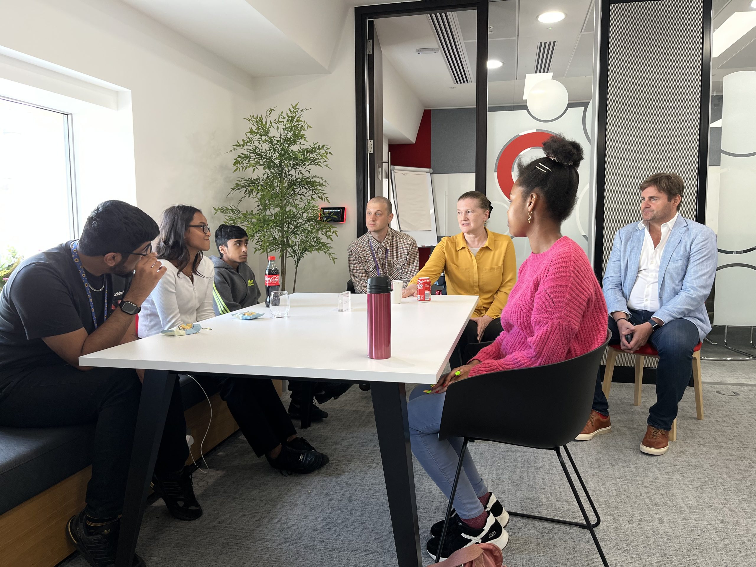 group of young people sat around an table in a professional setting