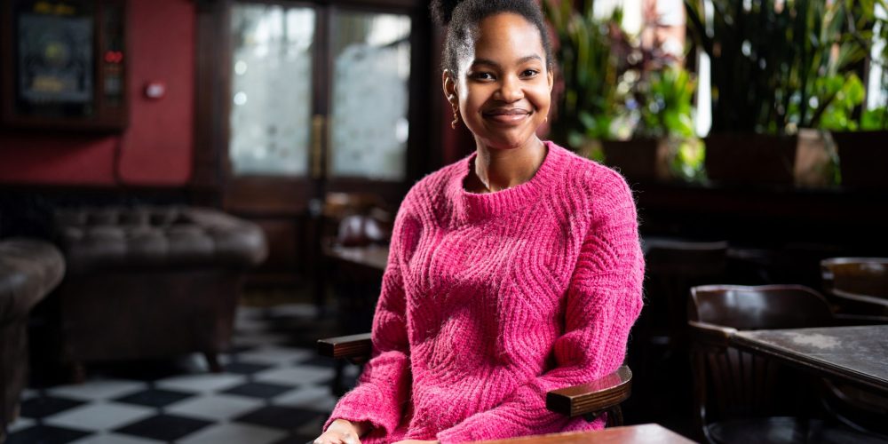 girl in pink jumper smiling at a table