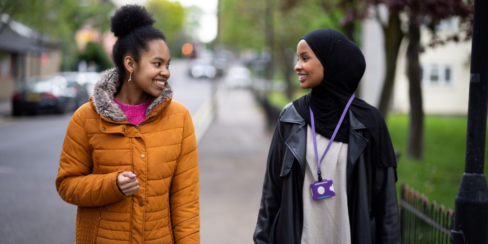 two young women walking down the street smiling