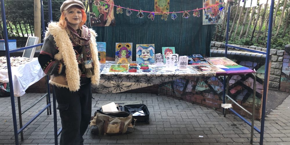 girl standing at market stall selling artwork