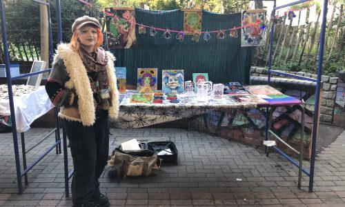 girl standing at market stall selling artwork