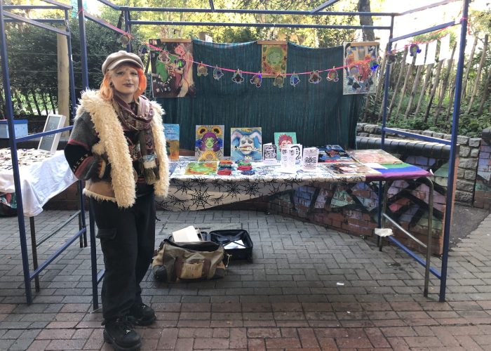 girl standing at market stall selling artwork