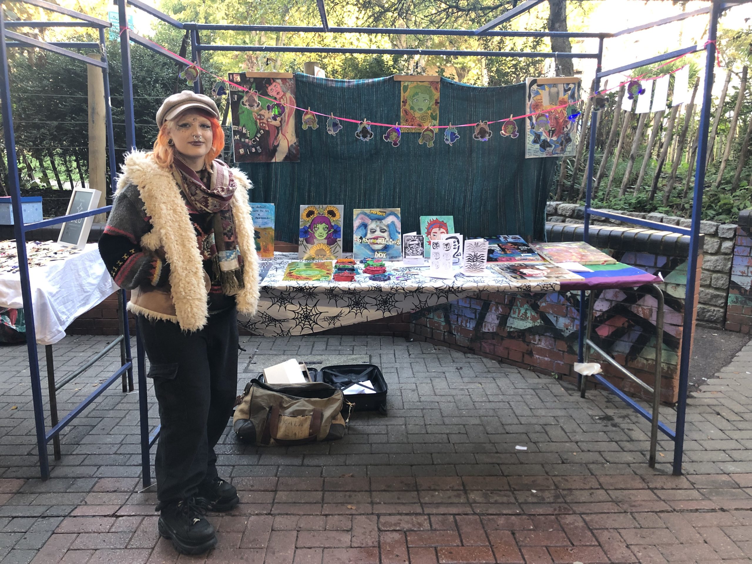 girl standing at market stall selling artwork