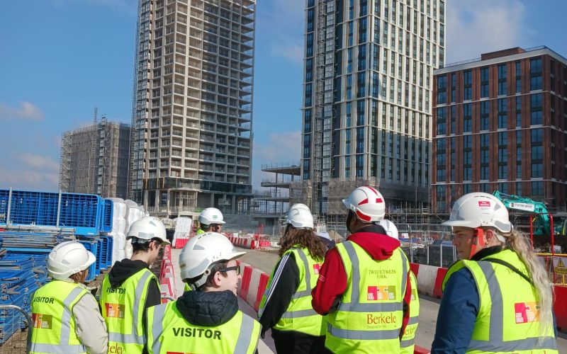 a group of young people on a construction site in high vis with helmets