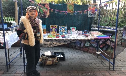 woman standing by market stall selling art pieces