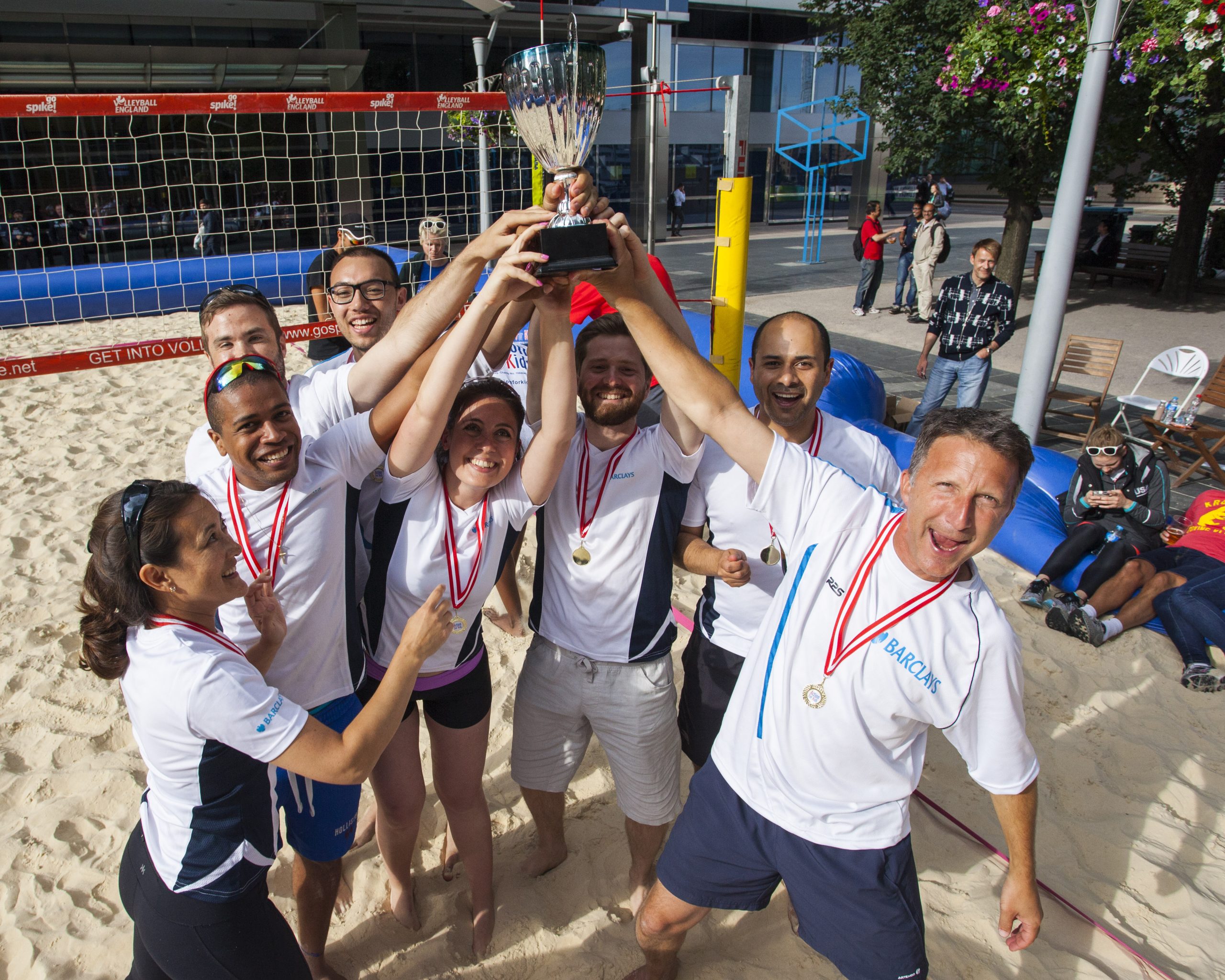 group of people smiling on sand with medals in the sun