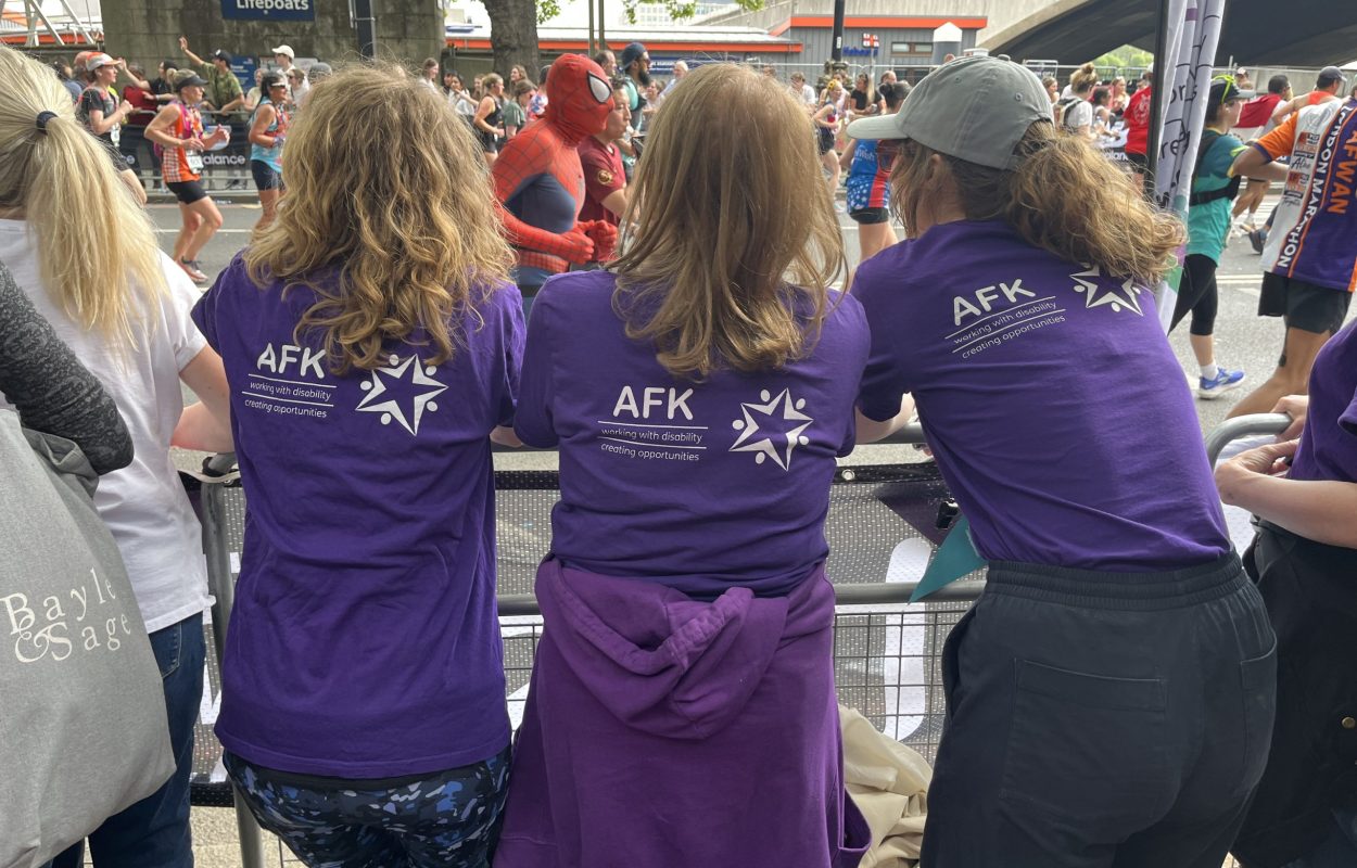 Three marathon spectators facing the london marathon with purple AFK t-shirts