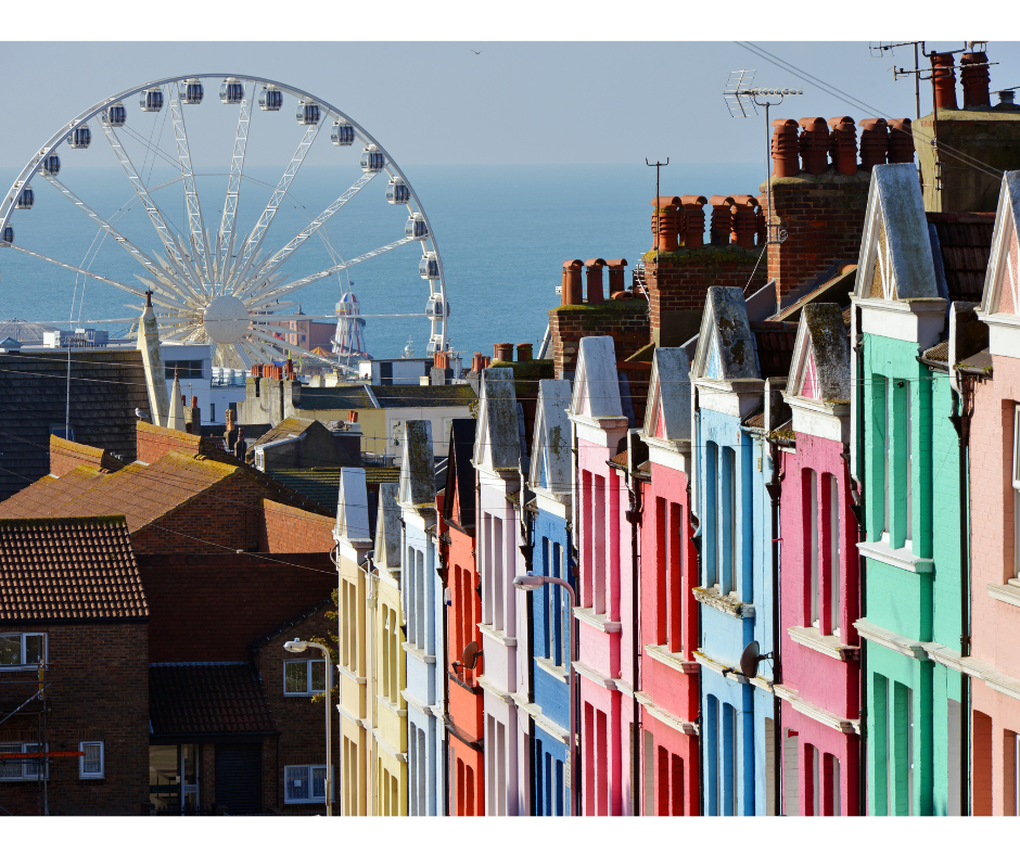 row of colourful houses out on to the sea with a ferris wheel on the seafront