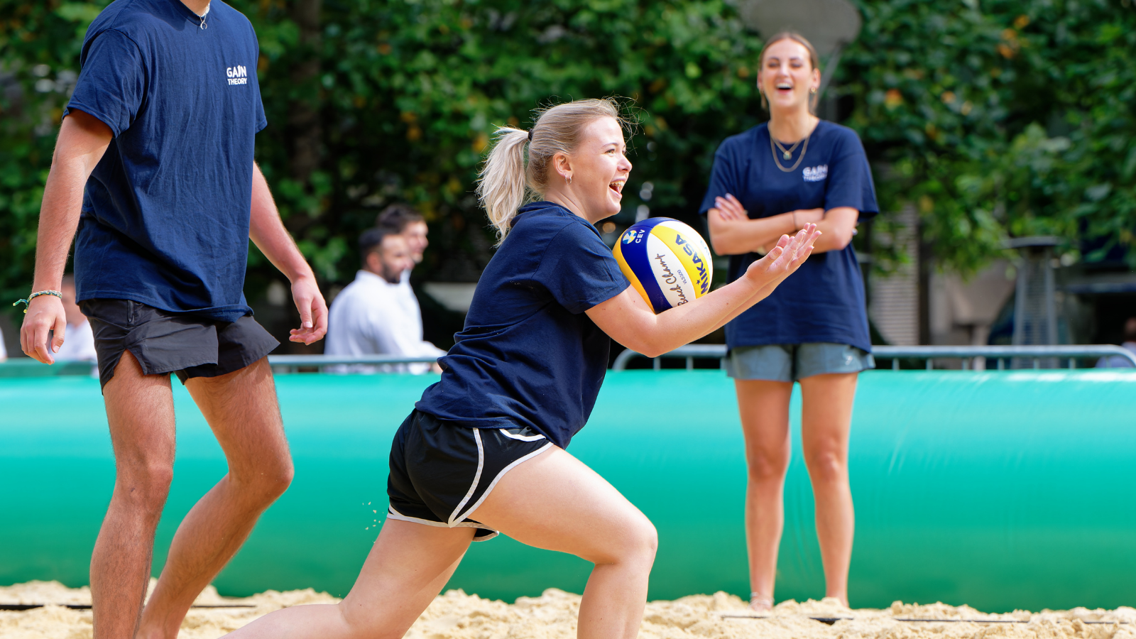 AFK Beach player receives the ball A player crouches on the sand while holding a volleyball during an AFK Beach match.