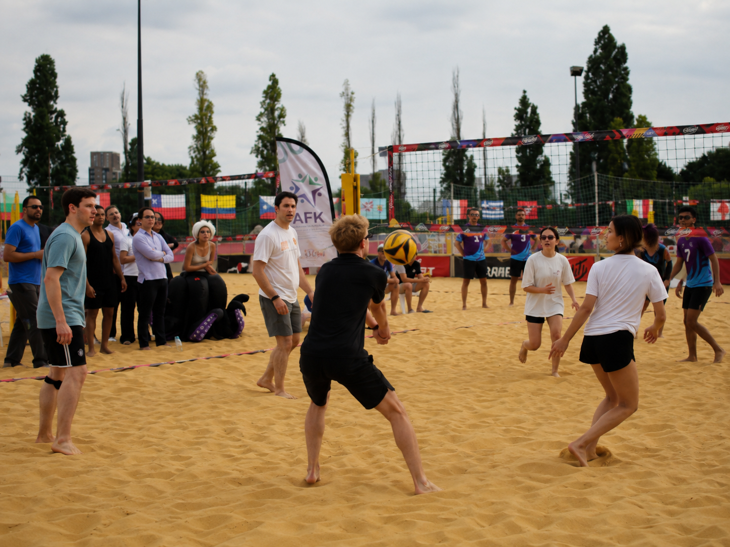 Players competing in a beach volleyball match at AFK Beach 2026, with spectators watching from the sidelines.